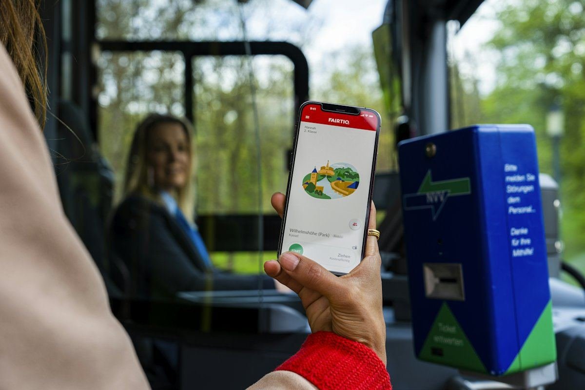 A passenger holding a smartphone beside the ticket machine on a tram in Kassel