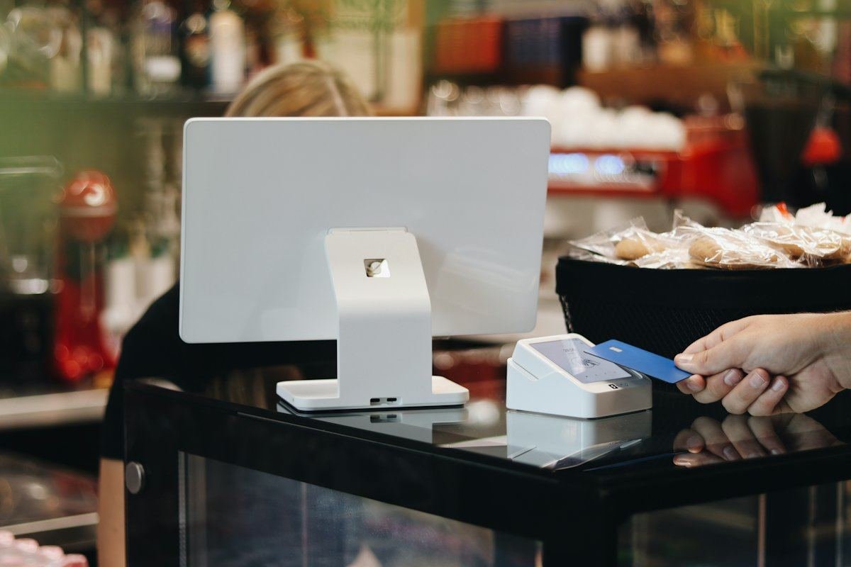 A customer paying by contactless card at a bakery café counter