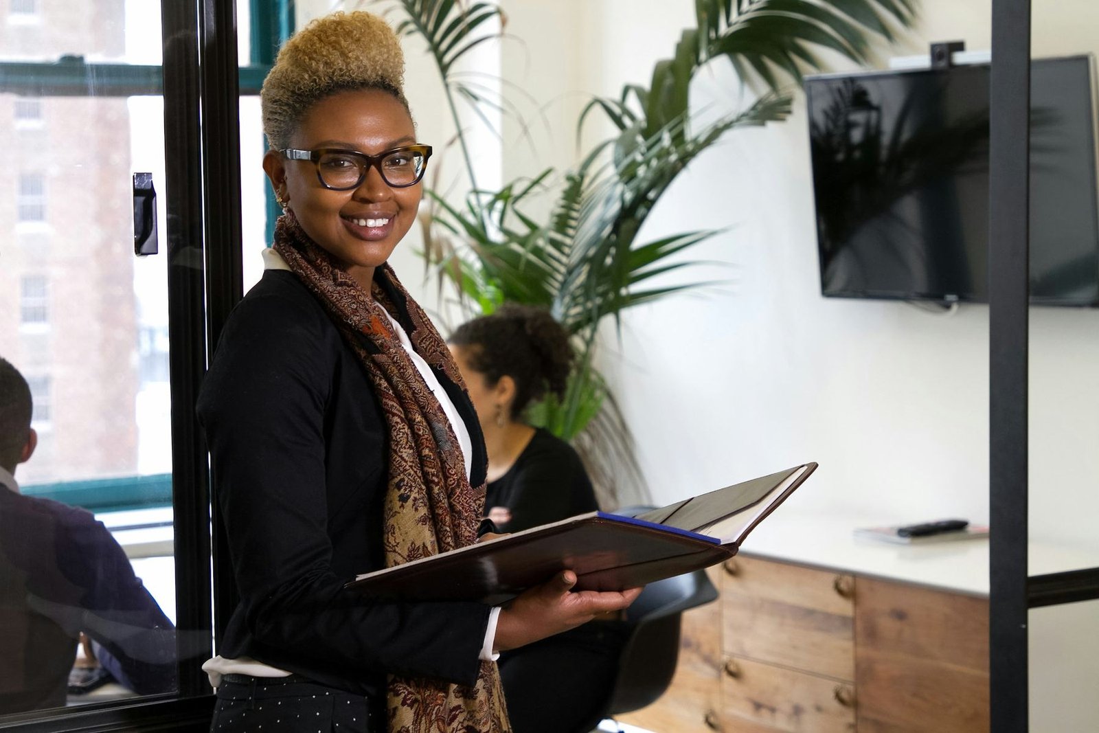 A professional woman holding a binder in a bright office